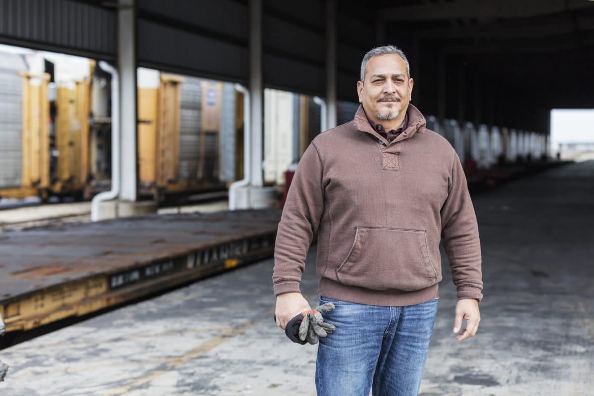 A man standing outside a warehouse while unable to work.