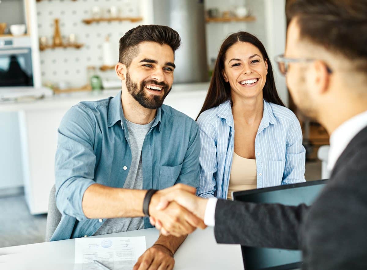 A couple shakes hands with a defective drugs lawyer after he helps them receive justice for their case.