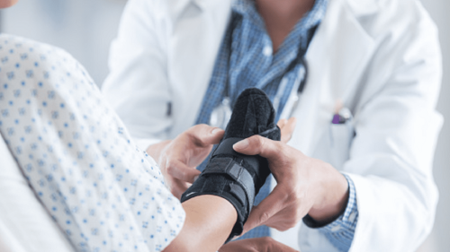 A nurse secures a brace around a patient’s hand and wrist.