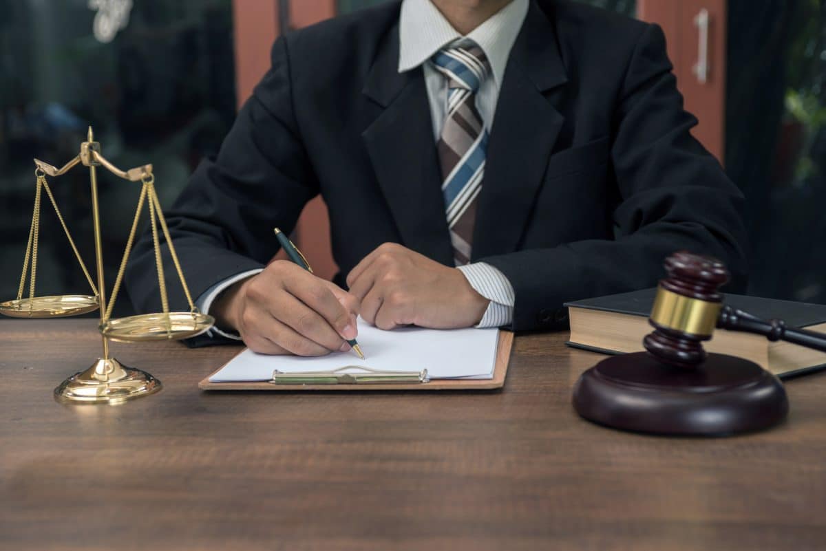 A trustworthy attorney sits behind a desk taking notes.