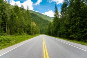 Road Through a Forest in the Mountains and Blue Sky with Clouds