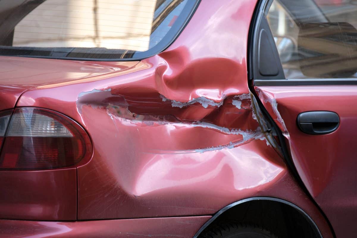 Close-up view of a red sedan with damage to the rear right side