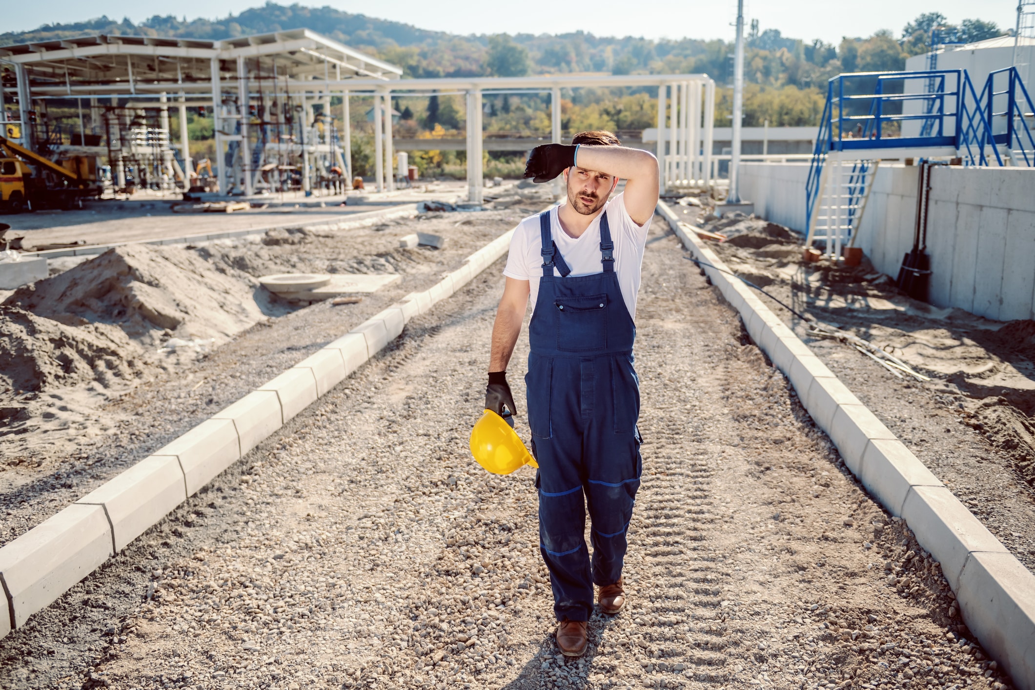 A construction worker wiping the sweat from his forehead.