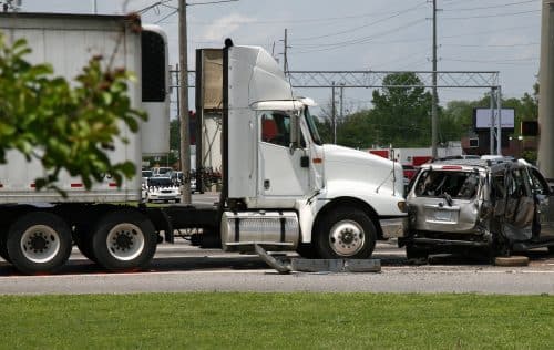 White semi-truck crashing into the back of a silver SUV on the road in Orange Beach