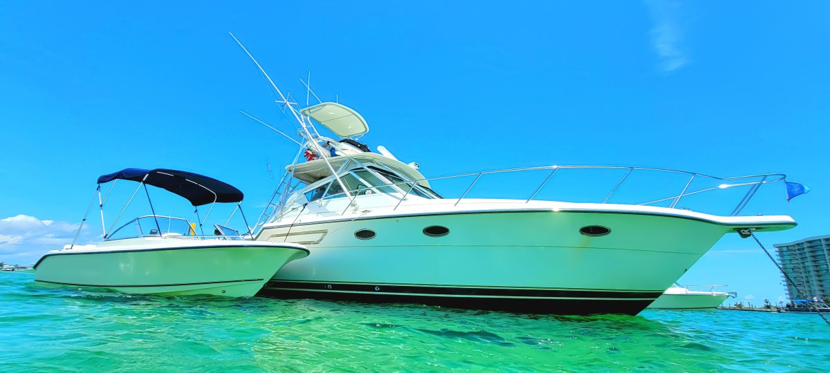 Three boats of varying sizes are anchored along a sandbar.