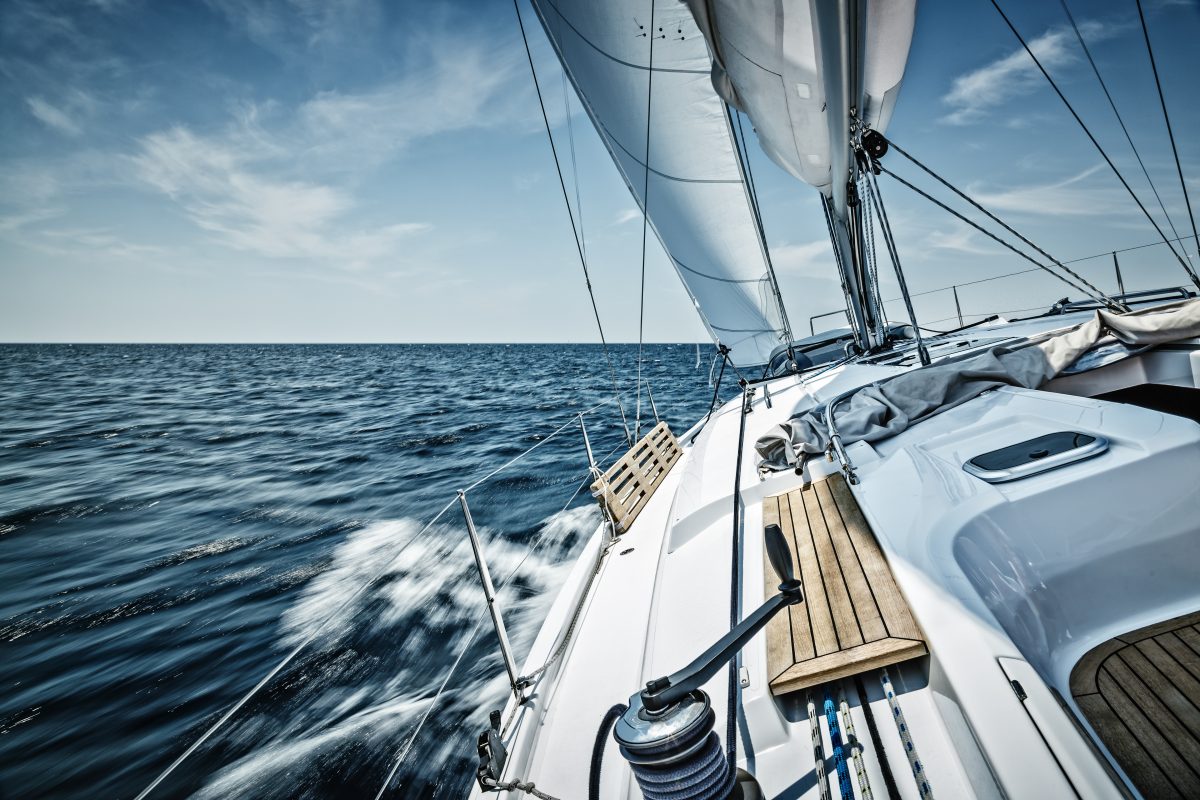 A sailboat leans to the side as it sails along rough waters.