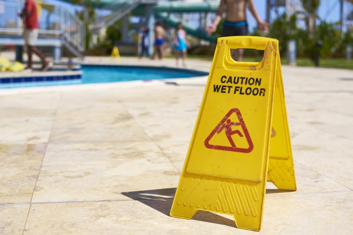 Yellow wet floor caution sign at public pool